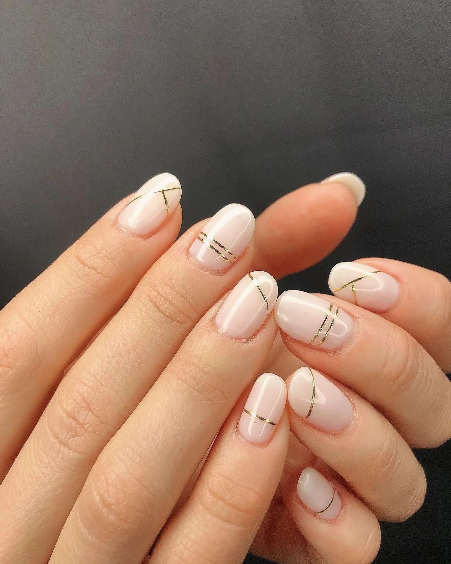 короткие овальные ногти с молочной основой и двумя параллельными золотыми линиями