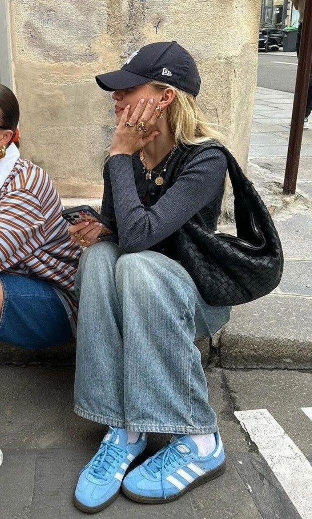 Блакитні замшеві кеди з білими смугами і темною підошвою під широкими світлими джинсами